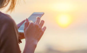 Someone uses their phone whilst watching a sunset